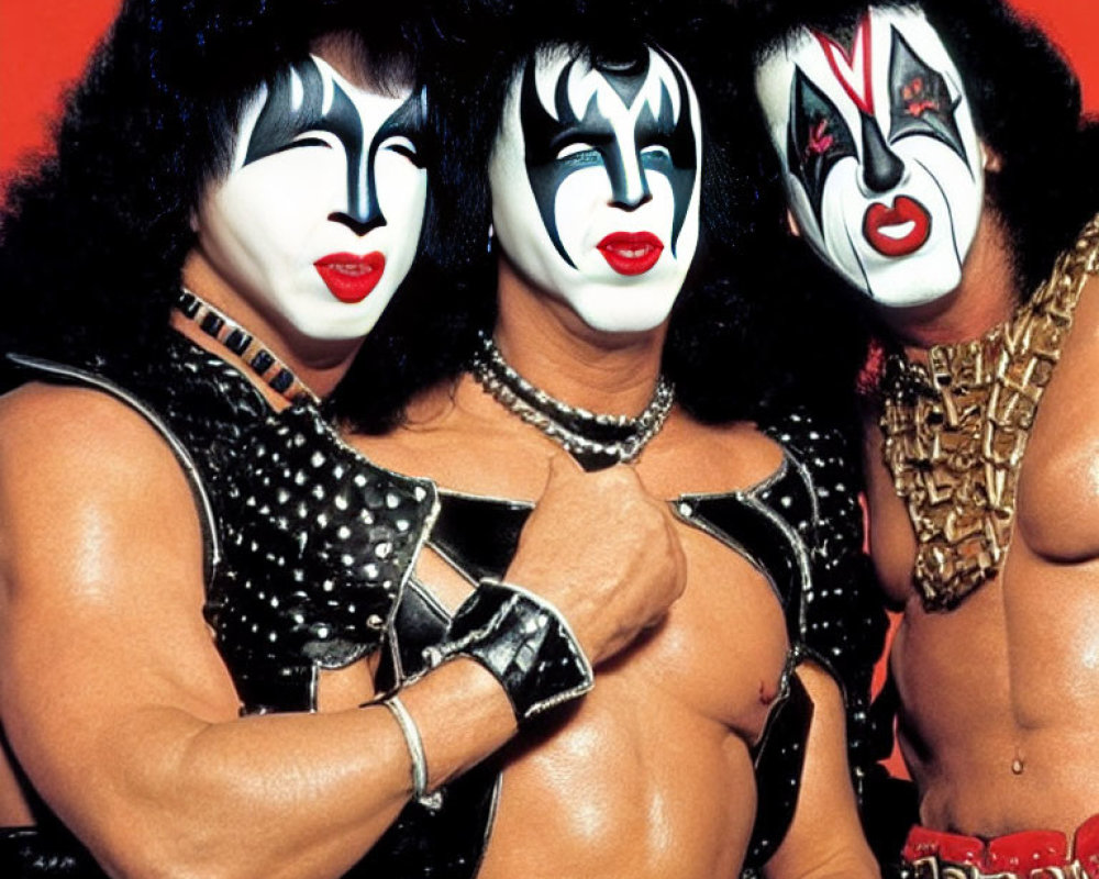 Band KISS members in iconic face paint and stage outfits on red background