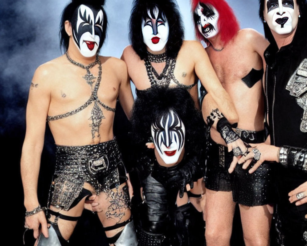 Four individuals in black and white face paint and rock outfits pose on smoky background