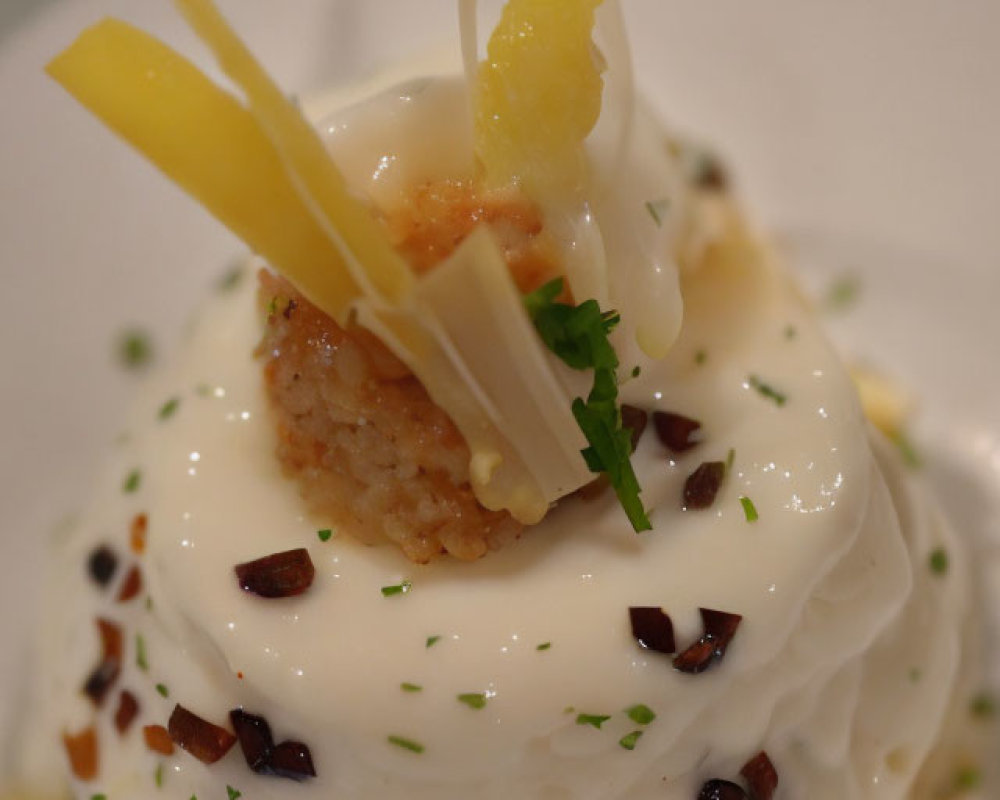 Creamy dessert with white sauce, mango slices, herbs, and crumbly bits