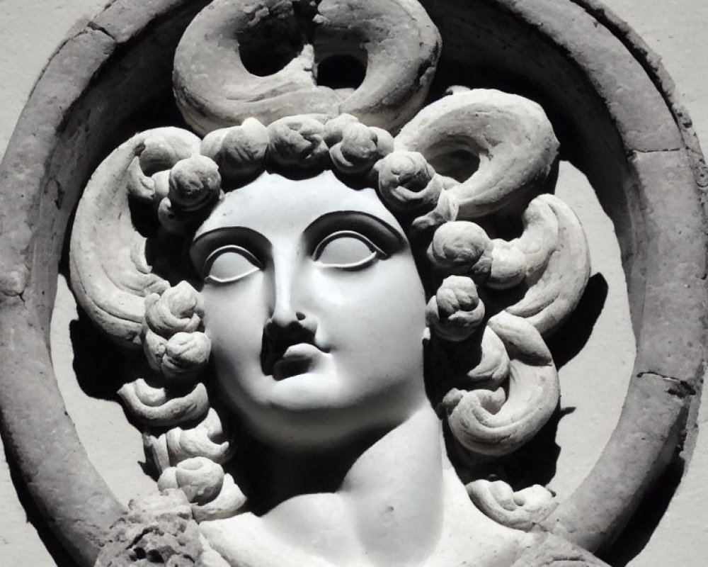 Stone bas-relief of woman's face with serpent hair in circular frame