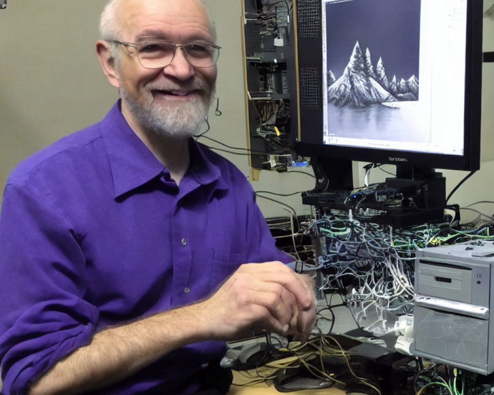 Smiling person in purple shirt near computer with mountain landscape on screen