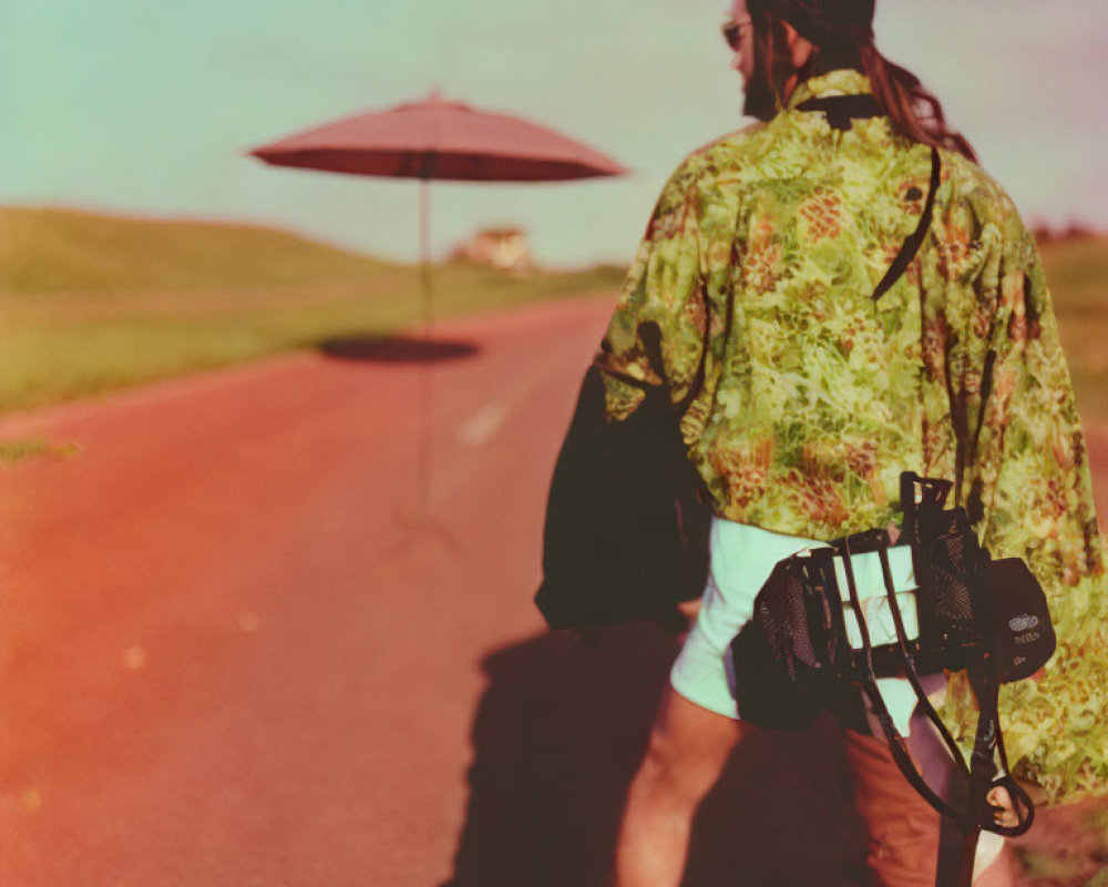 Photographer in green patterned outfit walking with red umbrella on road