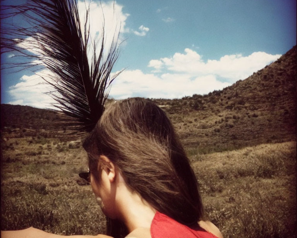 Woman in Red Top Standing in Grassy Field with Blowing Hair