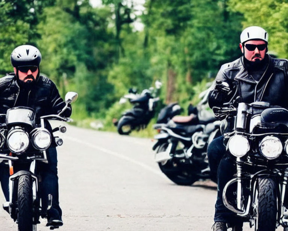 Motorcyclists in helmets and leather jackets on tree-lined road