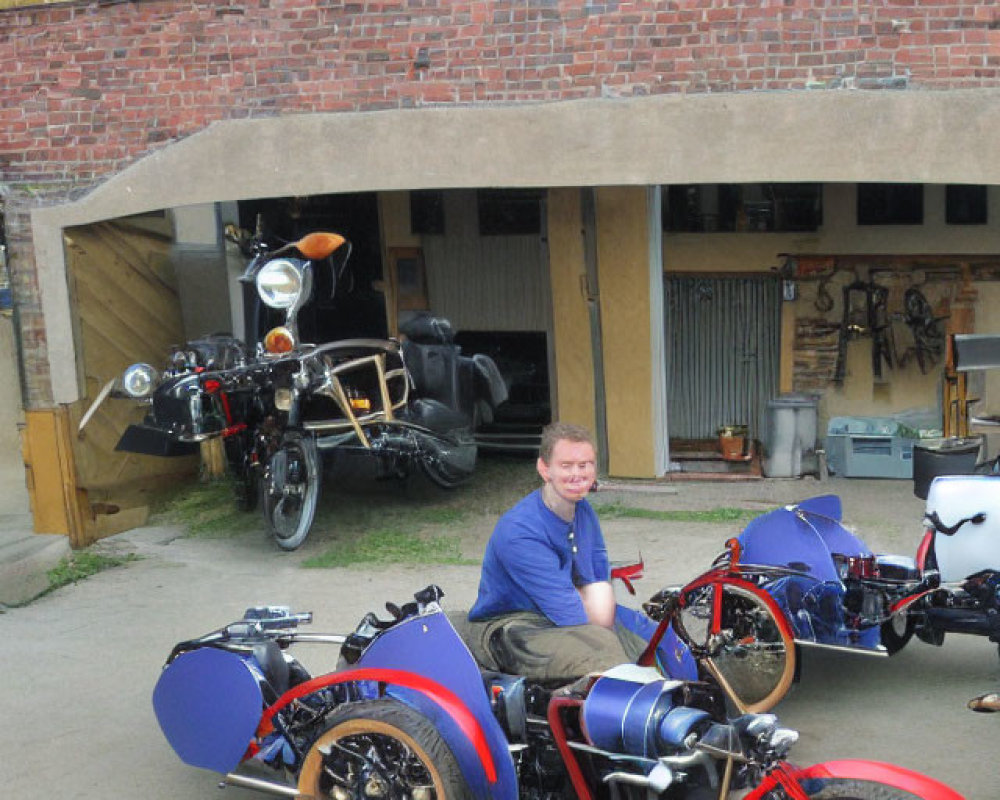 Man smiling on blue motorcycle with sidecar in front of motorcycle parts building