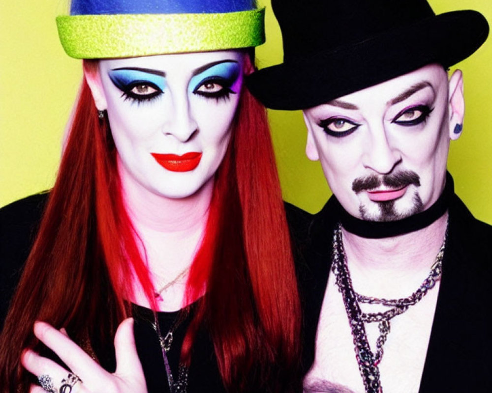 Dramatic makeup and hats on two people against yellow backdrop