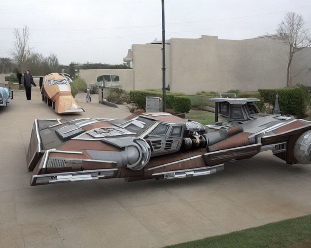 Life-sized outdoor display of X-wing fighter spaceship model with person nearby