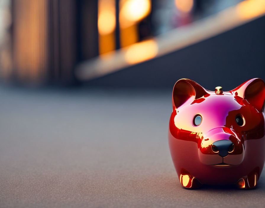 Shiny red bear-shaped piggy bank on city sidewalk