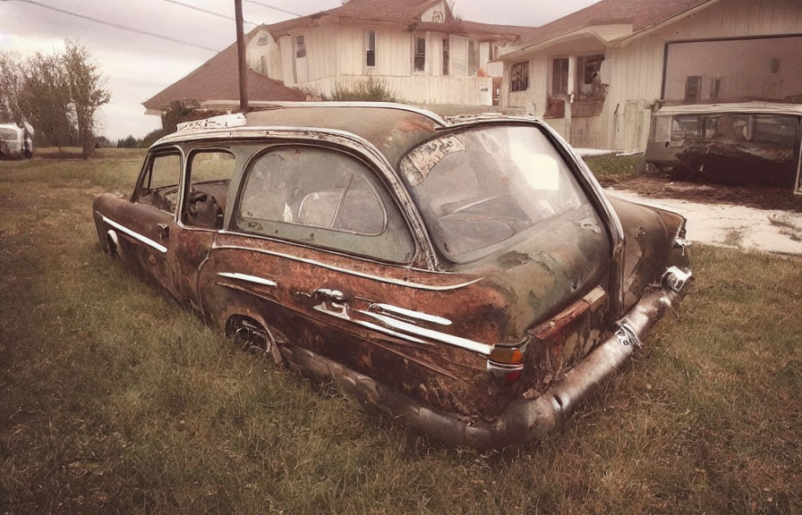 Abandoned rusty station wagon in grassy field under cloudy sky