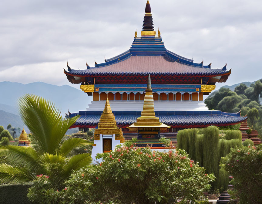 Asian temple with blue roofs, golden accents, greenery, and mountains