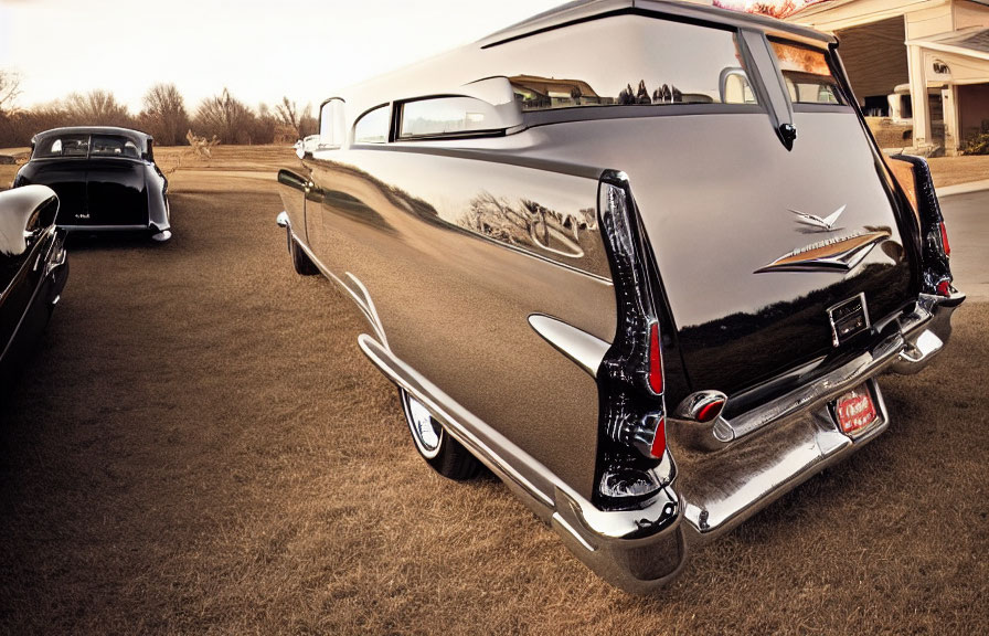 Vintage cars with distinctive tail fins and chrome details parked on a road under a soft sky.