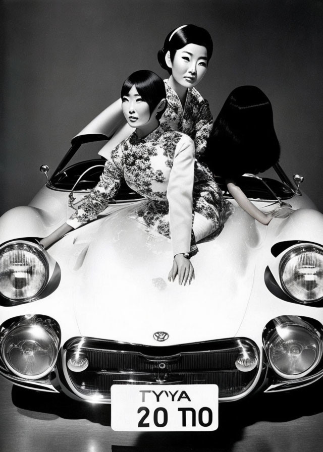 Two women in traditional Asian attire on vintage car hood with "TYIYA" plate