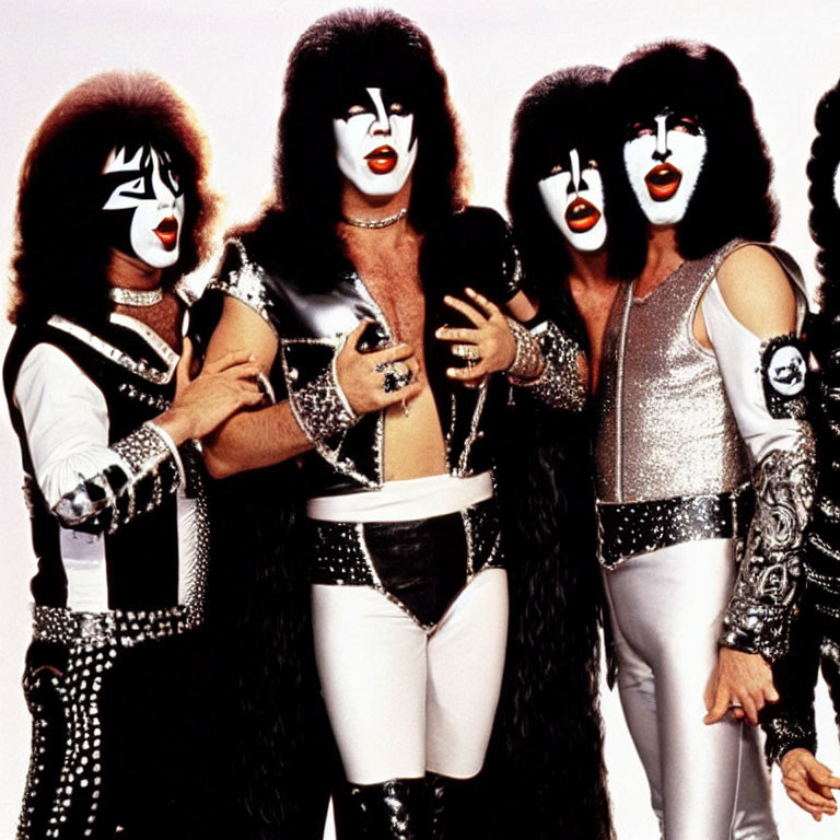 Group of four individuals in glam rock outfits and iconic face paint posing in black and silver costumes