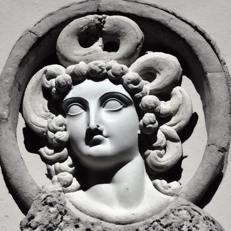 Stone bas-relief of woman's face with serpent hair in circular frame