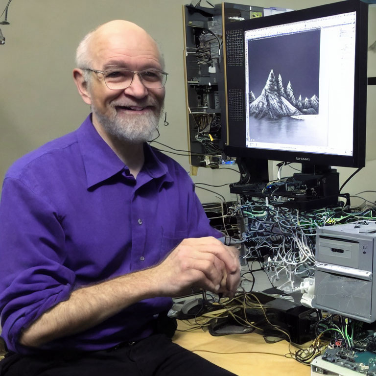 Smiling person in purple shirt near computer with mountain landscape on screen