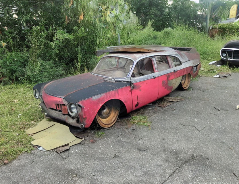 Abandoned red car with rust and peeling paint in overgrown setting