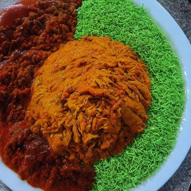 Colorful plate with red sauce, orange jollof rice, and green seasoned rice.