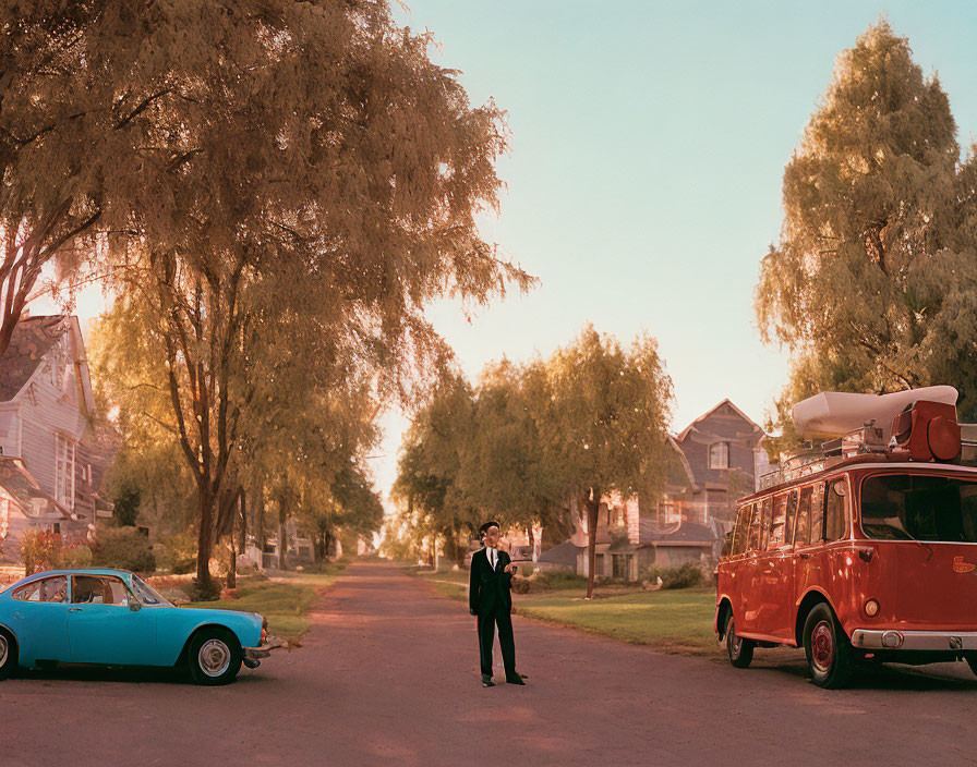 Business person on suburban street at dusk with vintage bus, canoe, and classic car.