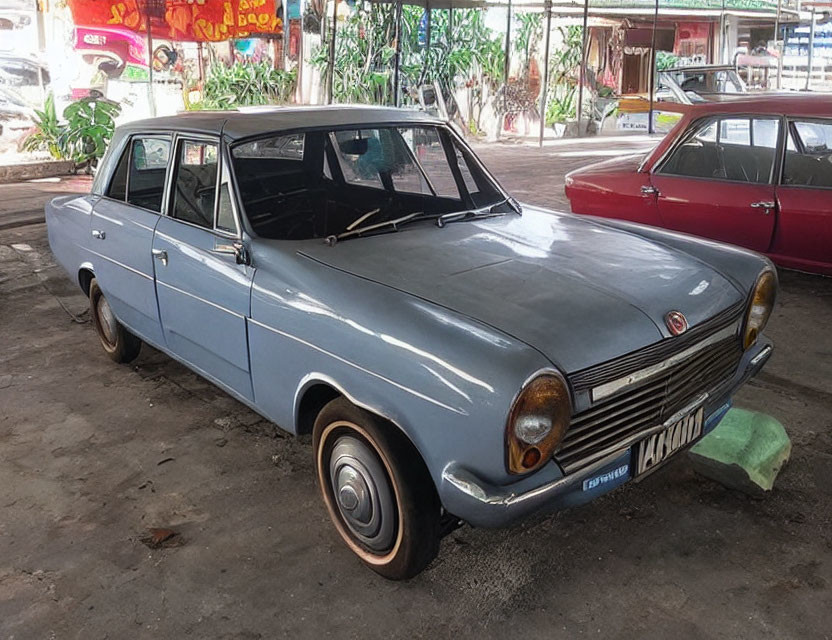 Vintage Light Blue Sedan with White Sidewall Tires on Concrete Floor