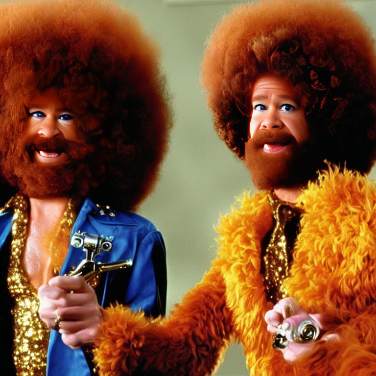 Two individuals in large afros and orange furry outfits in a humorous style.