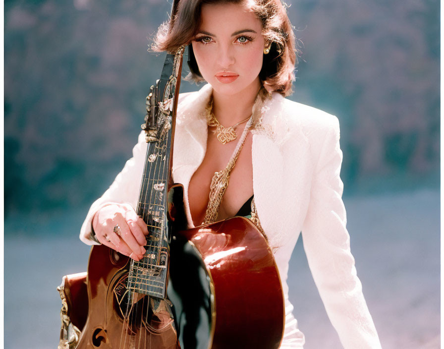 Dark-haired woman with guitar in white jacket and gold jewelry on blurred background