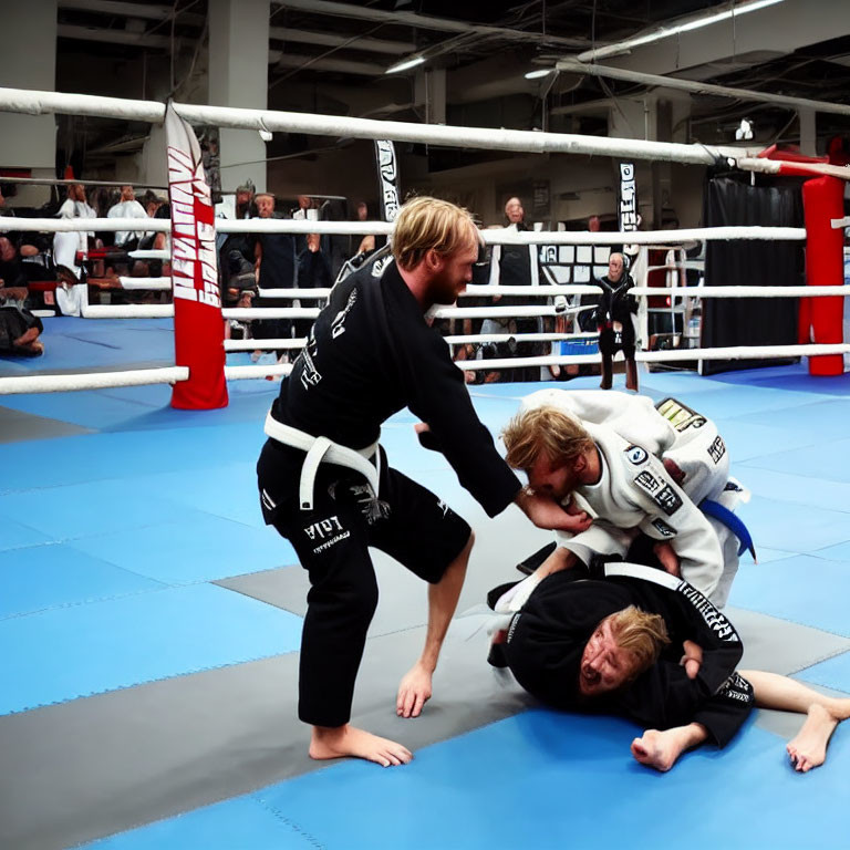 Brazilian Jiu-Jitsu practitioners in black and white gis in a dojo with spectators