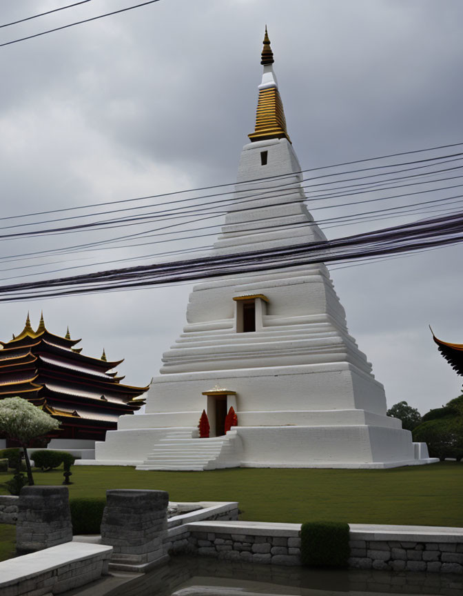 Traditional White Pagoda with Gold Spire Among Dark-Roofed Buildings