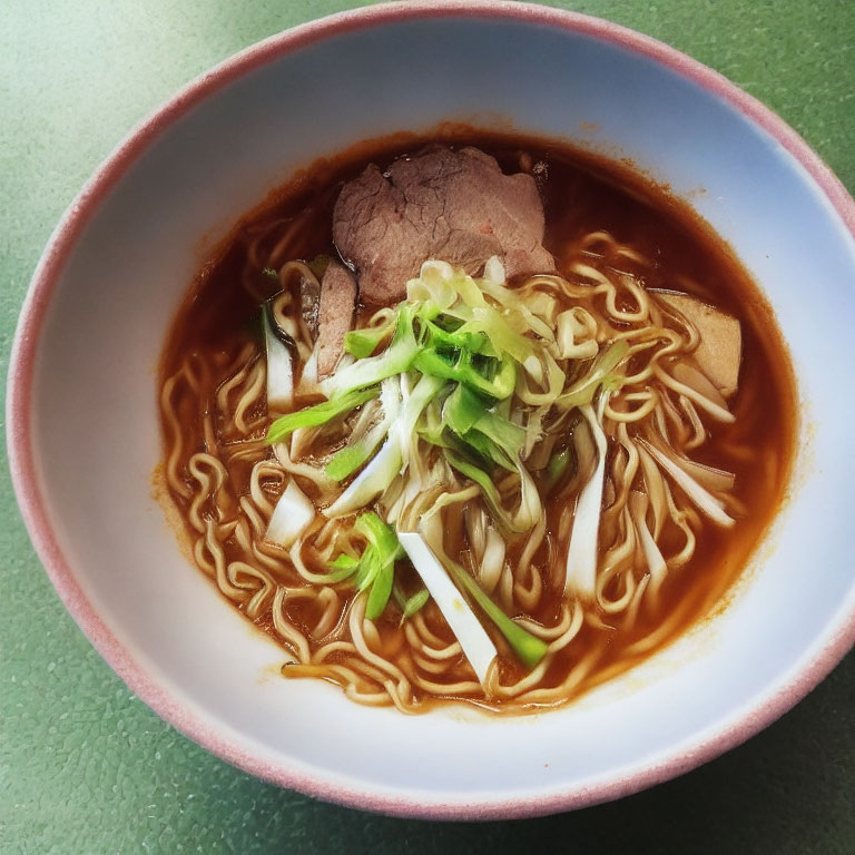 Savory ramen bowl with thin noodles, beef slices, scallions, and bamboo shoots