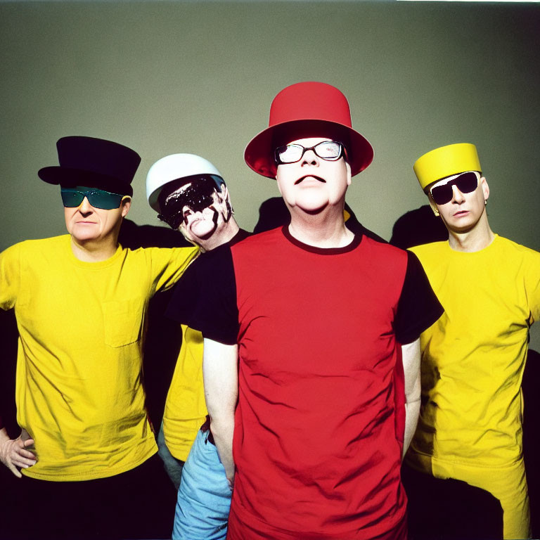 Four People in Bright Yellow T-Shirts and Colorful Hats on Green Background