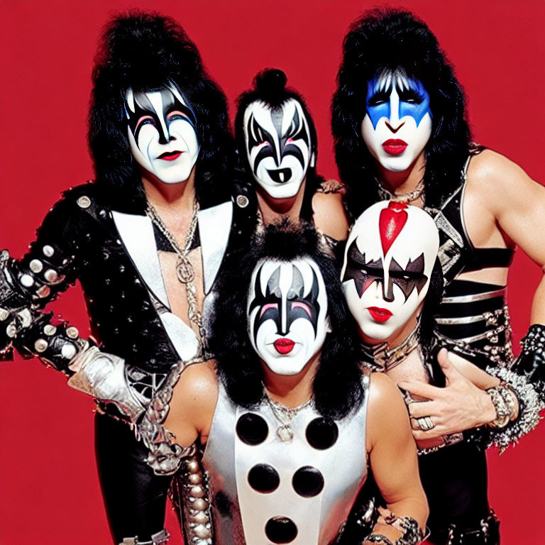 Four individuals in black and white face paint and rock costumes on red background