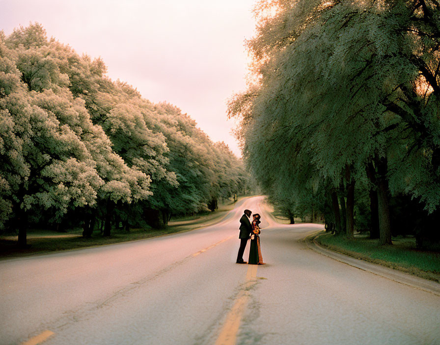 Embracing couple on deserted road surrounded by lush trees