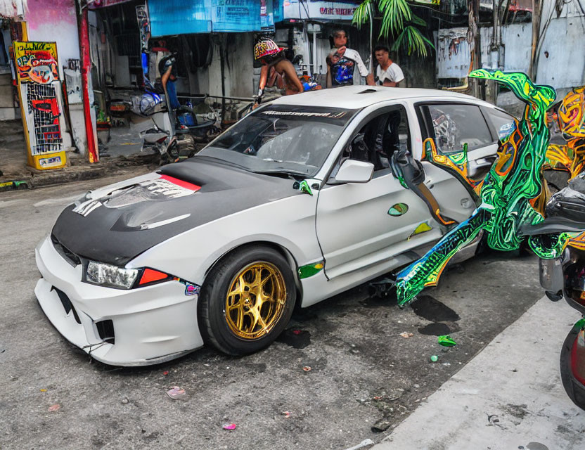 Custom Wide Body Sedan with Gold Rims and Graffiti Decals on City Street