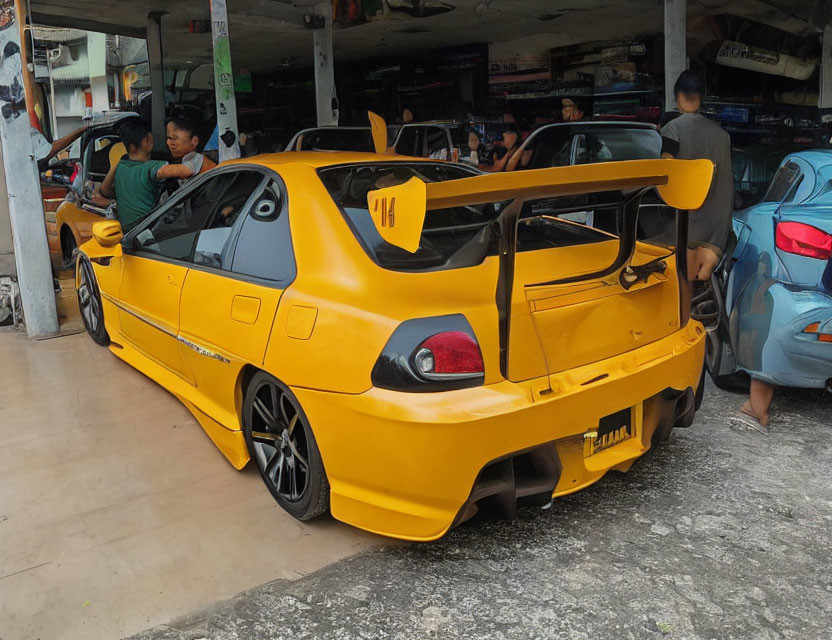 Yellow Sports Car with Large Rear Spoiler at Workshop Background