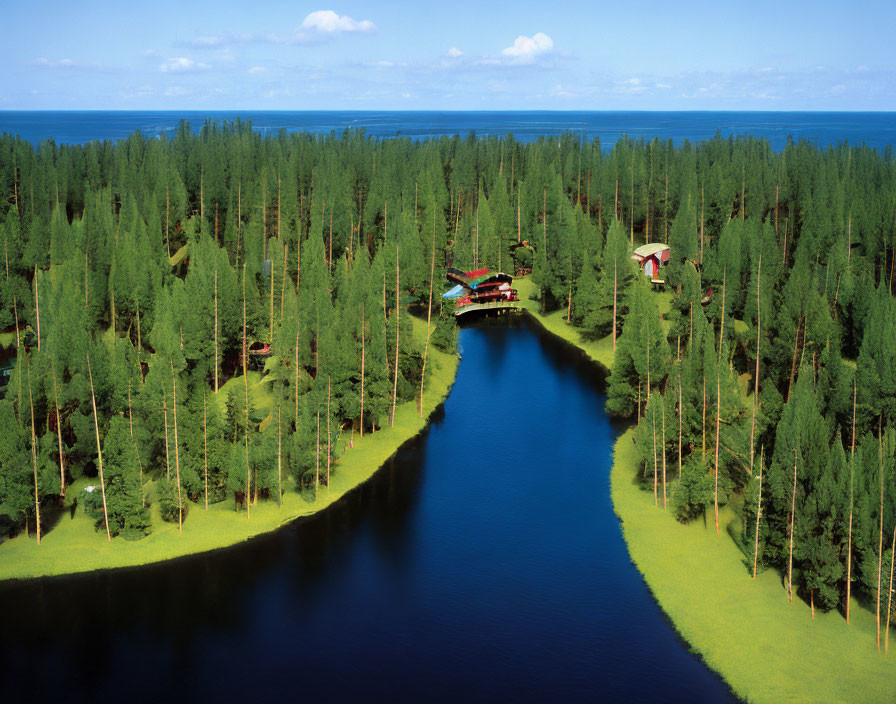 Tranquil lake, evergreen trees, buildings in forest under blue sky