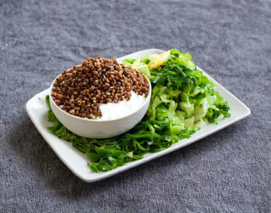 Bowl of Buckwheat on Chopped Lettuce and Herbs on Grey Surface