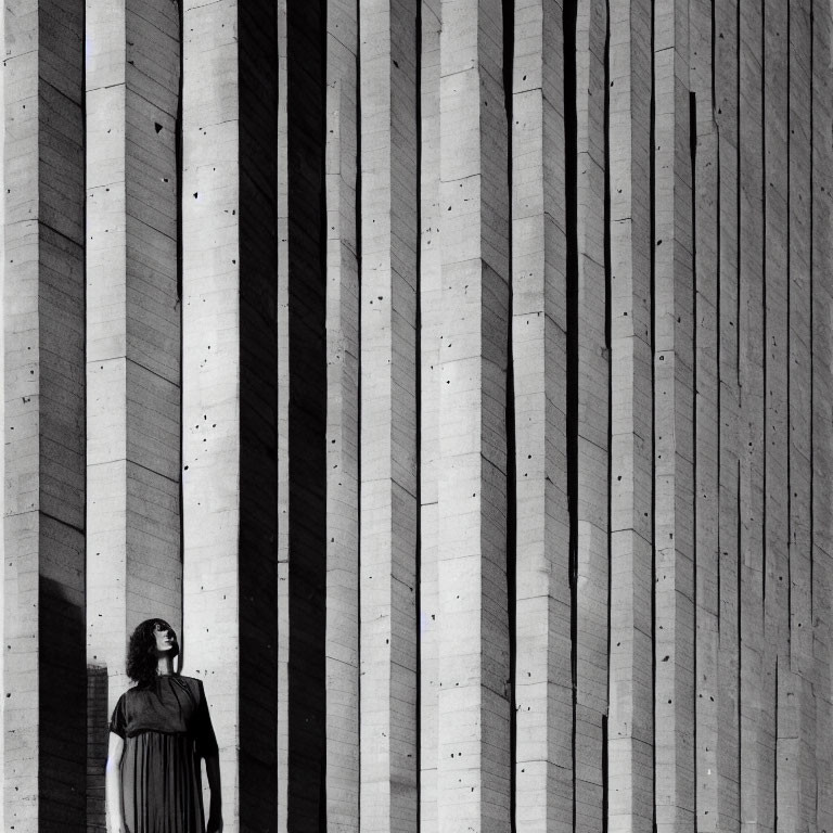 Woman Standing Before Large Wall with Concrete Stripes and Shadows