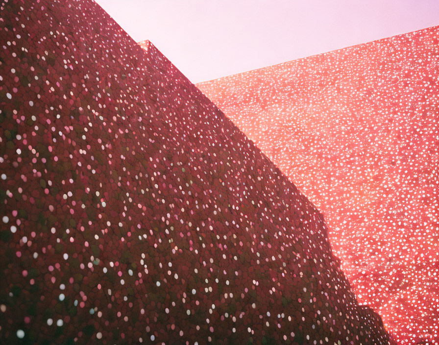 Textured wall with speckled pattern under pink lighting