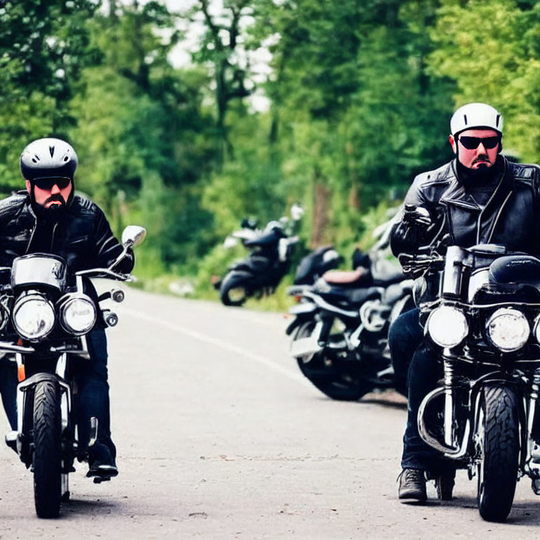 Motorcyclists in helmets and leather jackets on tree-lined road