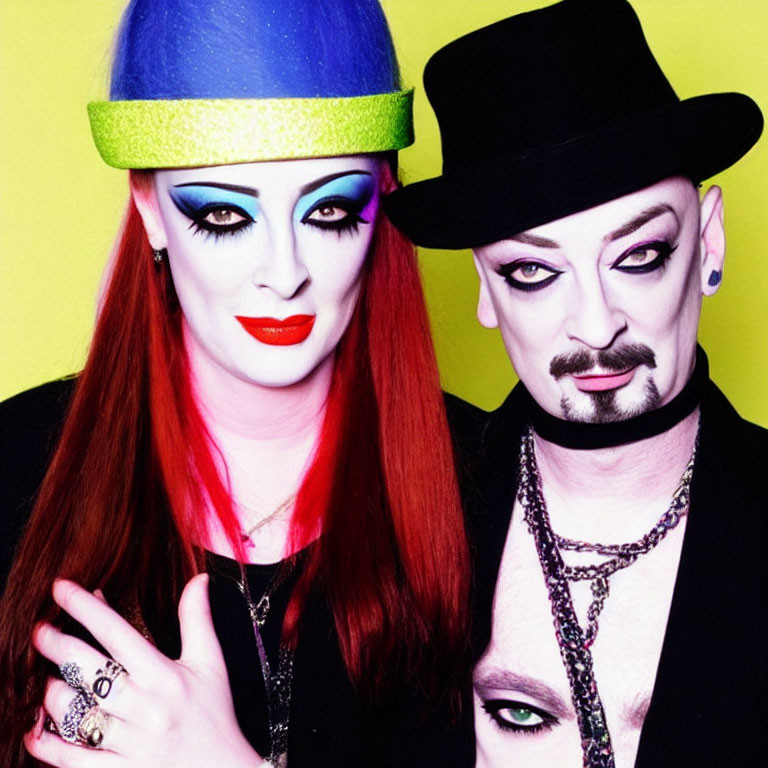 Dramatic makeup and hats on two people against yellow backdrop