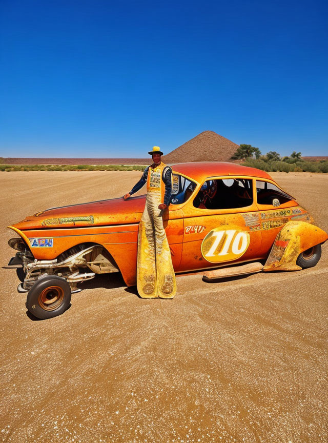 Vintage racing attire person leaning on rusty number 710 racer car in desert scenery