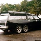 Vintage Cars Parked Outdoors: Black Sports Car with Round Taillights and Dual Exhausts