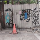 Urban mural of man in top hat painting wall with cone and flowers.