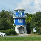 Scenic blue and white lighthouse painting near calm water