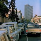 Vintage car by river with colorful buildings and skyscraper