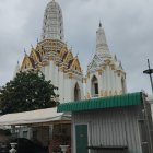 White temple with golden accents and tiered spires under hazy sky