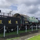 Vintage Steam Locomotive on Tracks with Cloudy Sky Showing Intricate Design and Metallic Textures