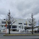 Blue house with circular patterns and organic shapes, vintage car parked under cloudy sky