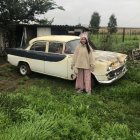 Colorful vintage car parked in front of whimsical cottage in lush garden