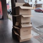 Person carrying tall stack of cardboard boxes on street