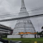 Traditional White Pagoda with Gold Spire Among Dark-Roofed Buildings